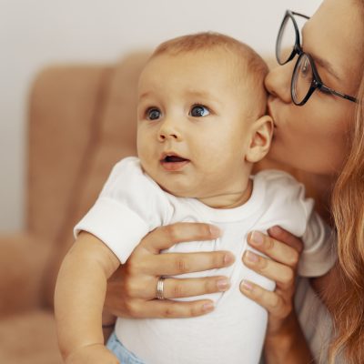 Happy family, mother and baby having fun together at home on the couch